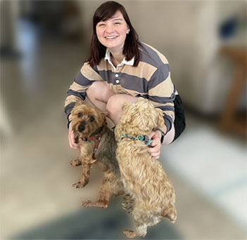 Pet Sitter Lindsey sitting down with two Yorkie dogs